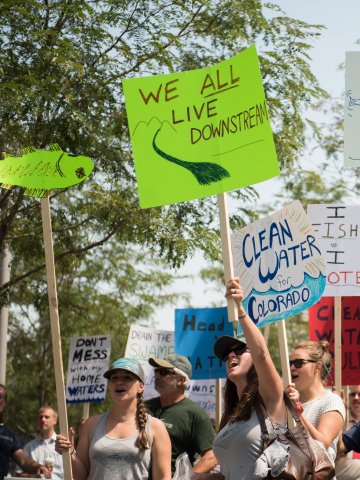 Rally crowd holding a sign that reads We all live downstream